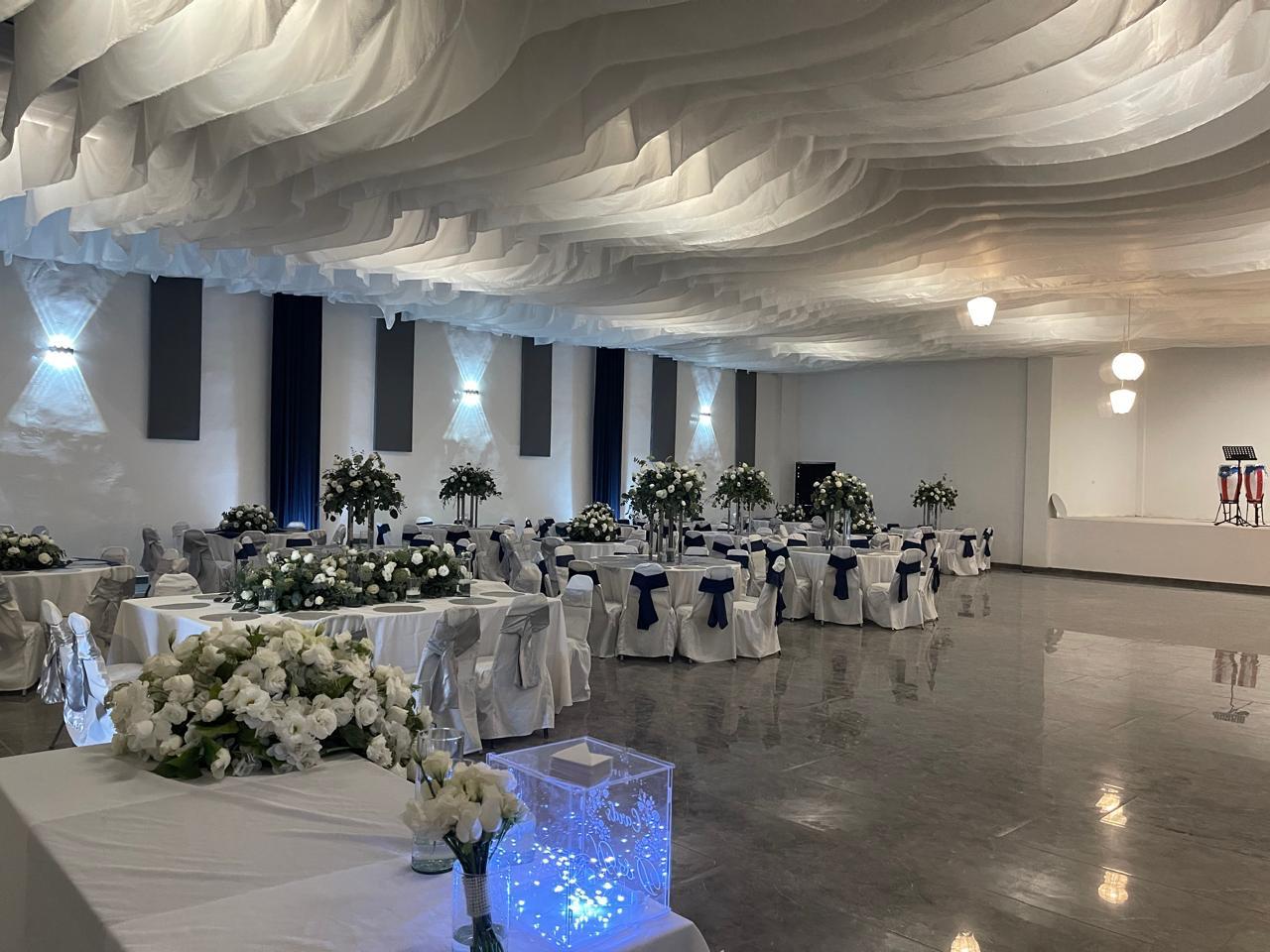 Salón de eventos decorado con mesas y arreglos florales