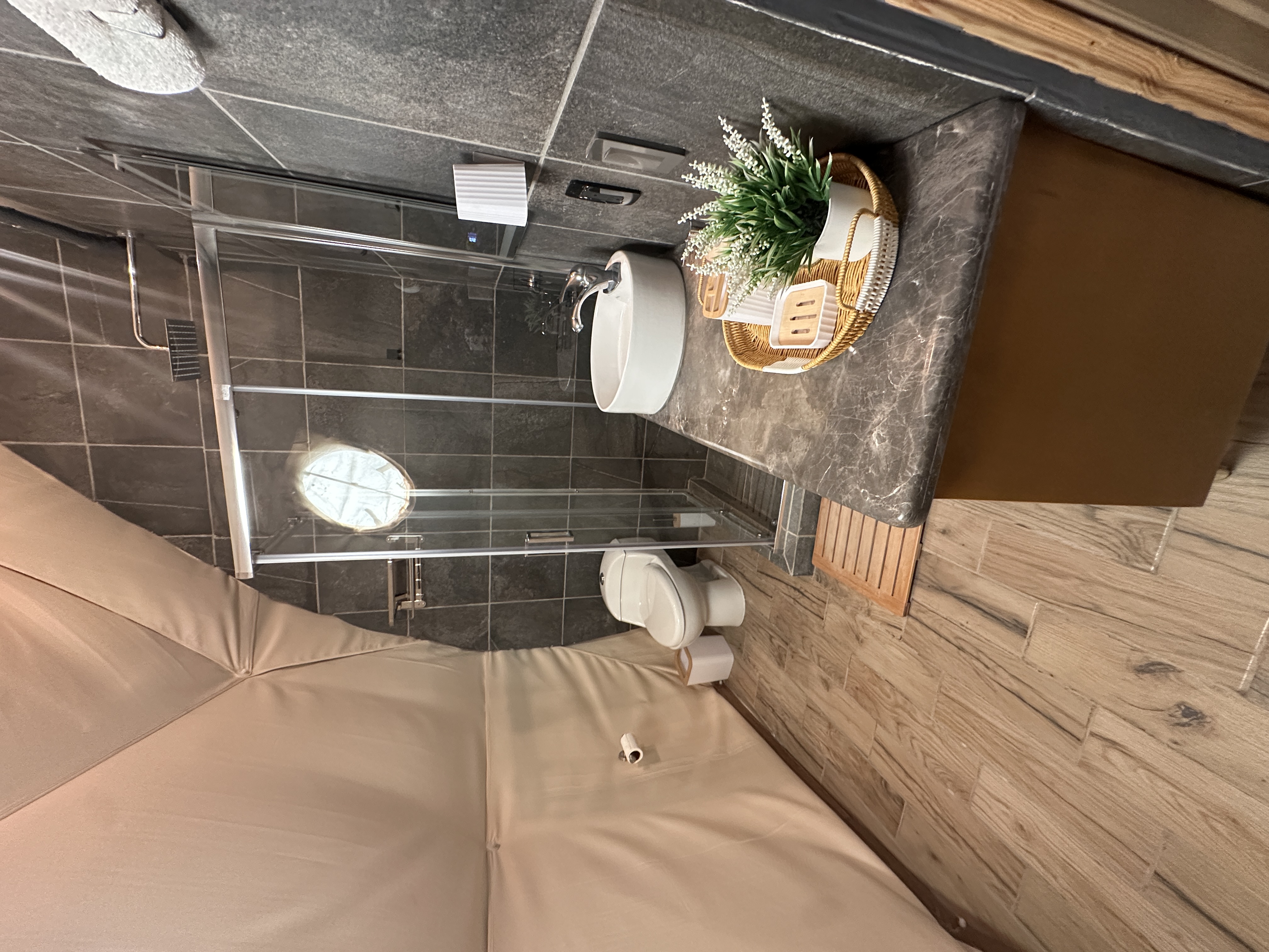 Baño completo con regadera de cristal dentro del glamping